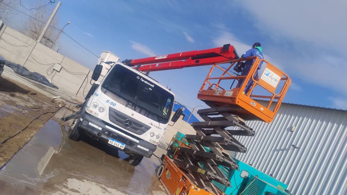 Camión con hidroelevador junto a una plataforma tijera en altura